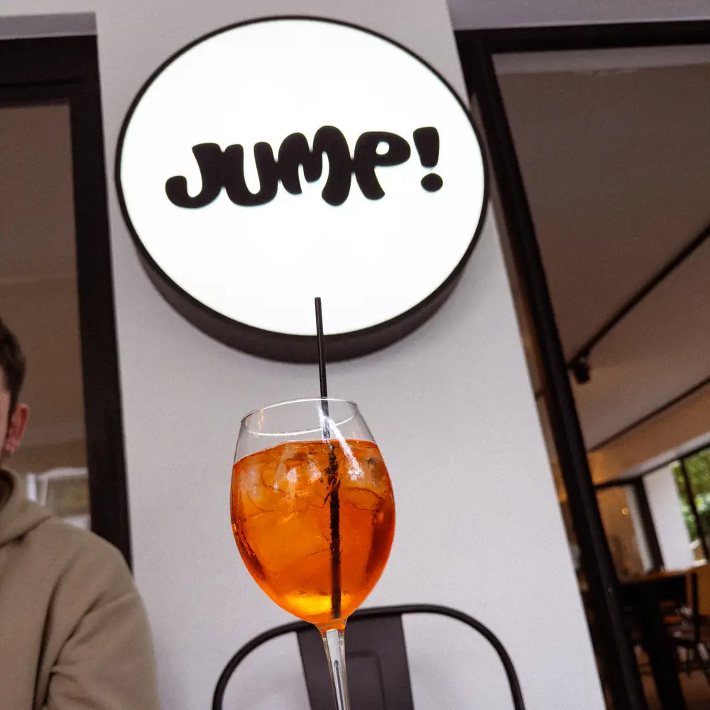 An Aperol spritz on a table beneath the Jump! sign