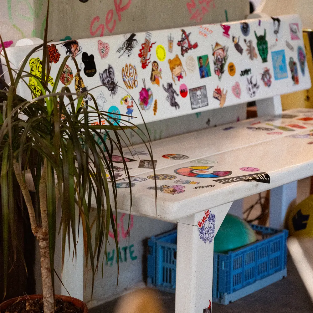 The sticker-covered bench against the graffiti wall